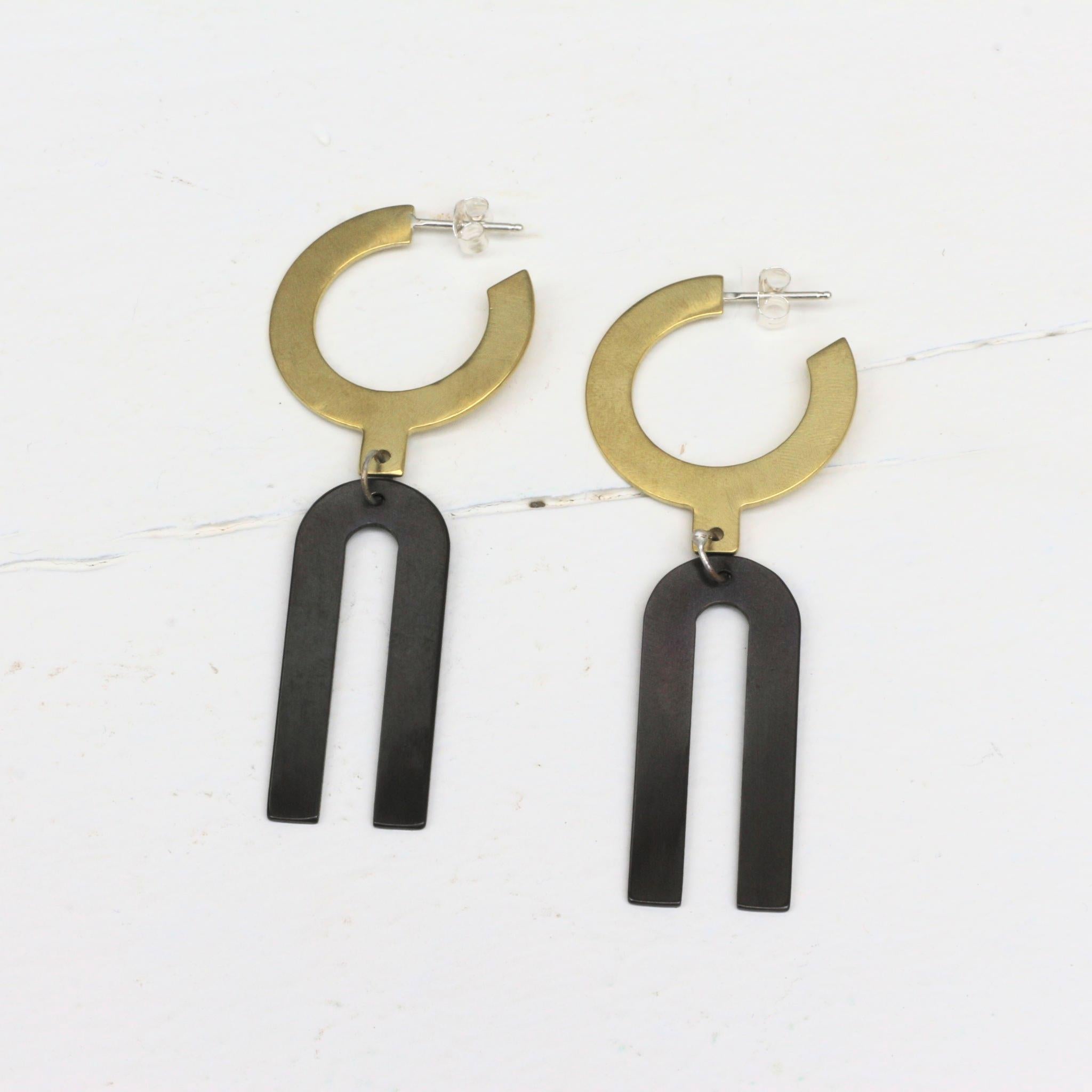Boucles d'oreilles en laiton et laiton oxydé modèle exclusif arkhe avec des formes géométriques, réalisées en collaboration avec la créatrice de bijoux américaine Natalie Joy. Brass and oxydized brass earrings, exclusive arkhe style, developed in collaboration with American jewelry designer Natalie Joy.