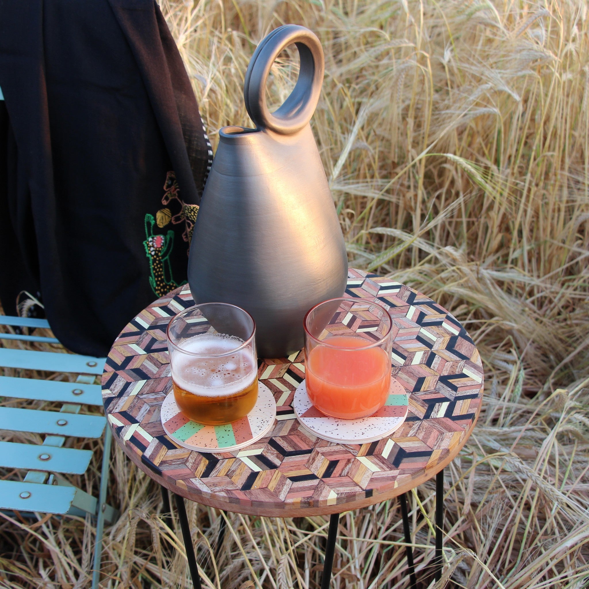Femme dans un champ de blé portant une étole en pashmina noire brodée réalisée en collaboration avec Laïte Works. Woman in a wheat field wearing a black embroidered pashmina stole, in collaboration with Laïte Works.