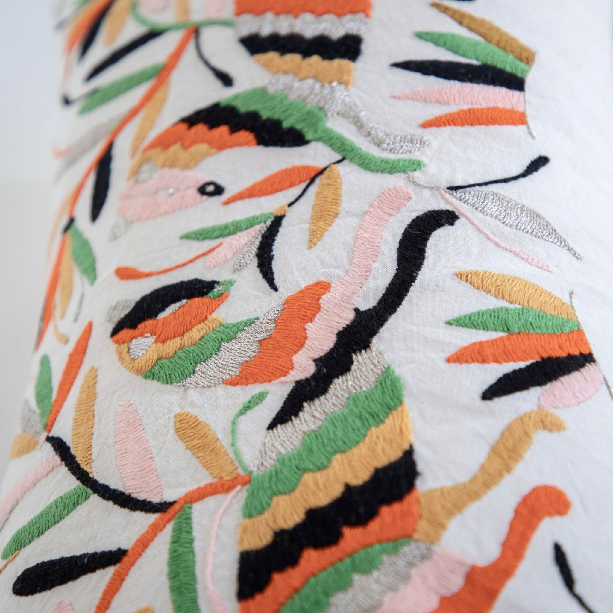Coussin brodé en otomi en collaboration avec l'atelier folklore, posé sur un fauteuil rose Lloyd Loom et une peau de mouton. Otomi embroidered cushion in collaboration with l'atelier folklore, laying on a Lloyd Loom pink chair and a sheep skin.