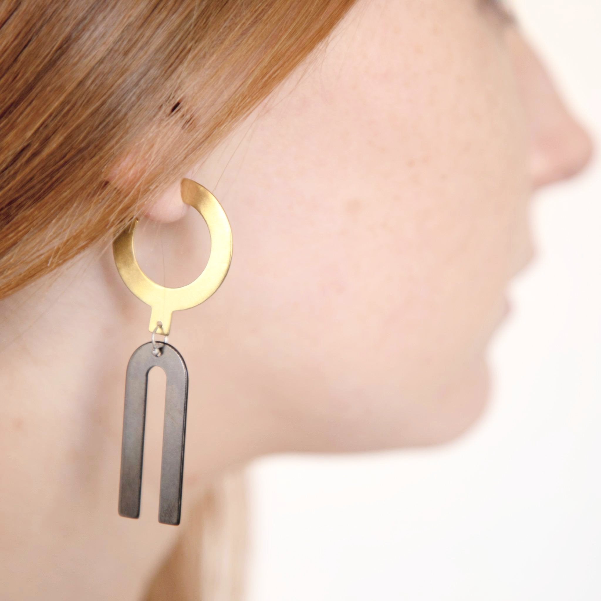 Boucles d'oreilles en laiton et laiton oxydé modèle exclusif arkhe avec des formes géométriques, réalisées en collaboration avec la créatrice de bijoux américaine Natalie Joy. Brass and oxydized brass earrings, exclusive arkhe style, developed in collaboration with American jewelry designer Natalie Joy.