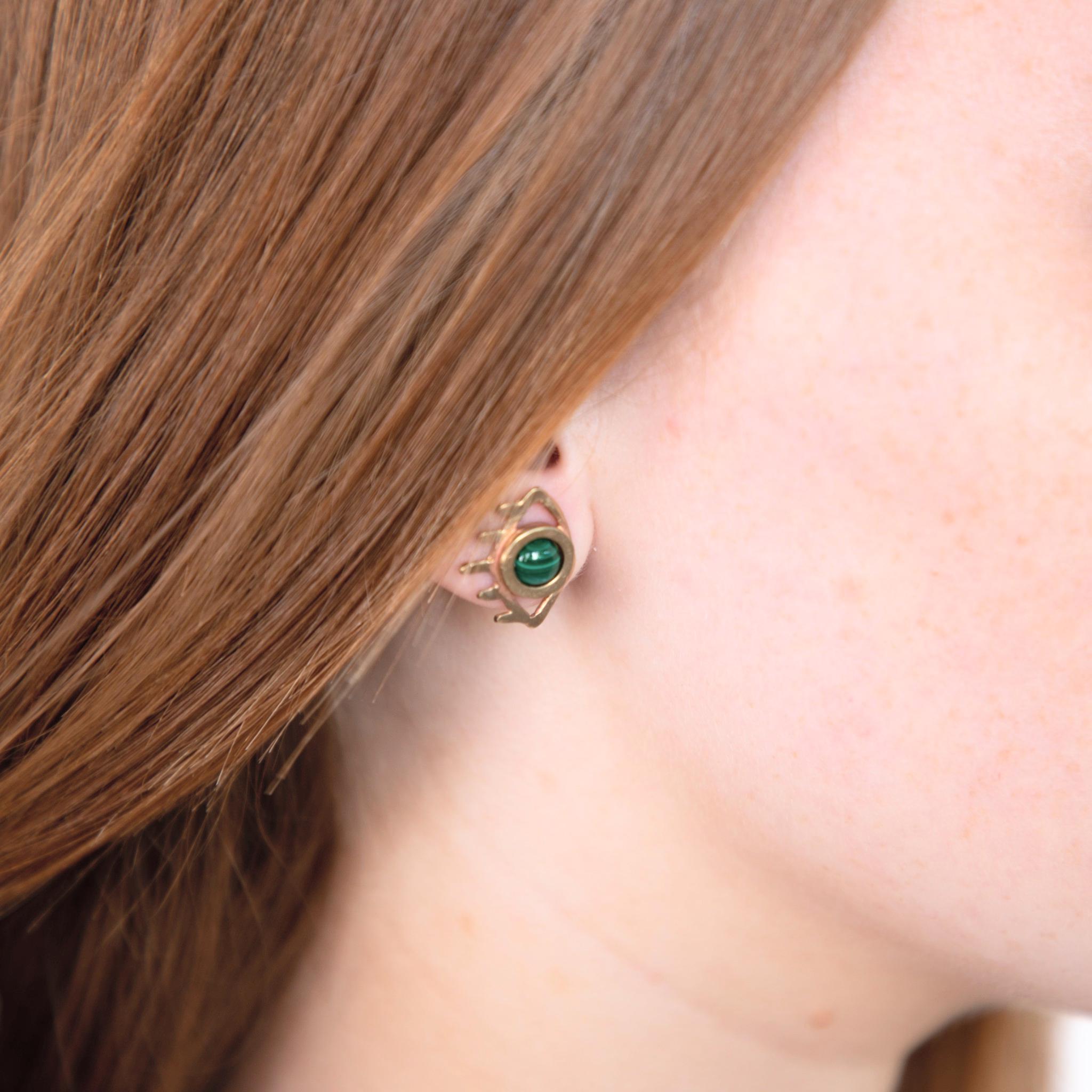 Femme aux cheveux roux ou blond vénitien portant des boucles d'oreilles oeil et pierre de malachite, fabriquées à Chicago par la créatrice THERESE KUEMPEL. Woman with ginger hair wearing eye and malachite earrings, handcrafted in Chicago by THERESE KUEMPEL.