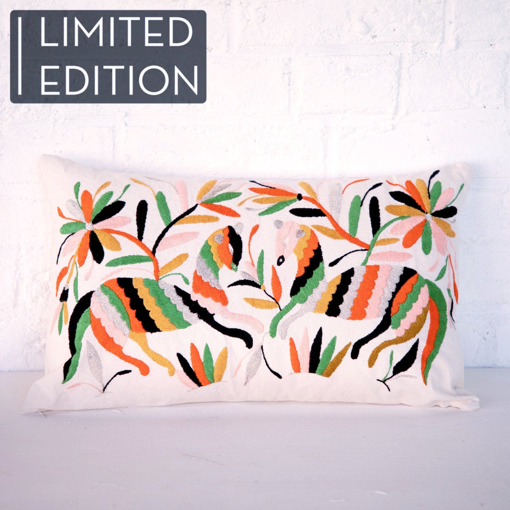 Coussin brodé en otomi en collaboration avec l'atelier folklore, posé sur un fauteuil rose Lloyd Loom et une peau de mouton. Otomi embroidered cushion in collaboration with l'atelier folklore, laying on a Lloyd Loom pink chair and a sheep skin.