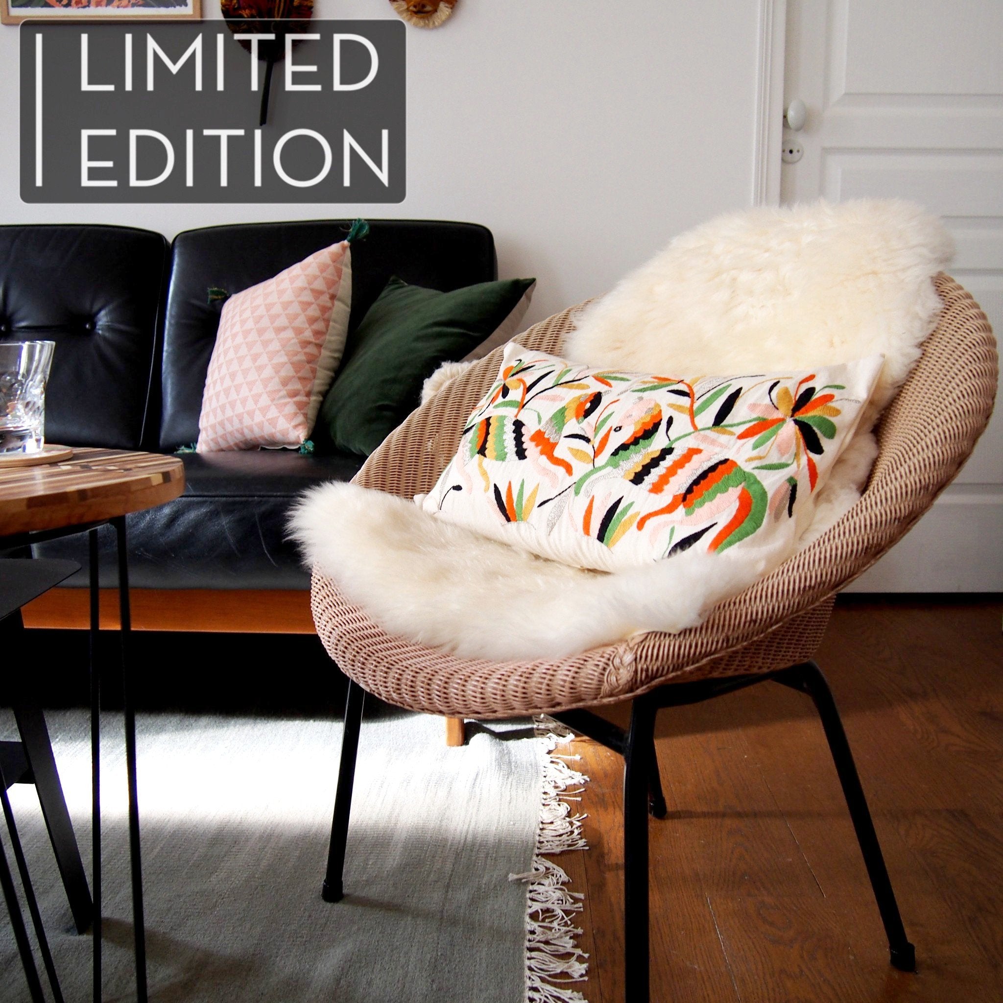 Coussin brodé en otomi en collaboration avec l'atelier folklore, posé sur un fauteuil rose Lloyd Loom et une peau de mouton. Otomi embroidered cushion in collaboration with l'atelier folklore, laying on a Lloyd Loom pink chair and a sheep skin.