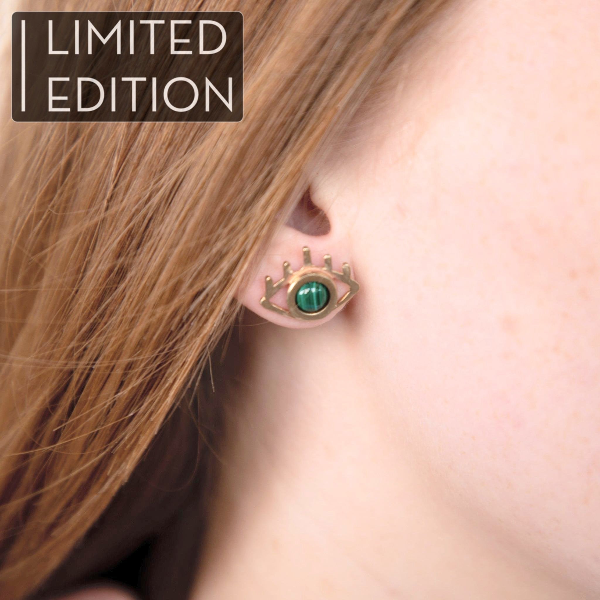 Femme aux cheveux roux ou blond vénitien portant des boucles d'oreilles oeil et pierre de malachite, fabriquées à Chicago par la créatrice THERESE KUEMPEL. Woman with ginger hair wearing eye and malachite earrings, handcrafted in Chicago by THERESE KUEMPEL.
