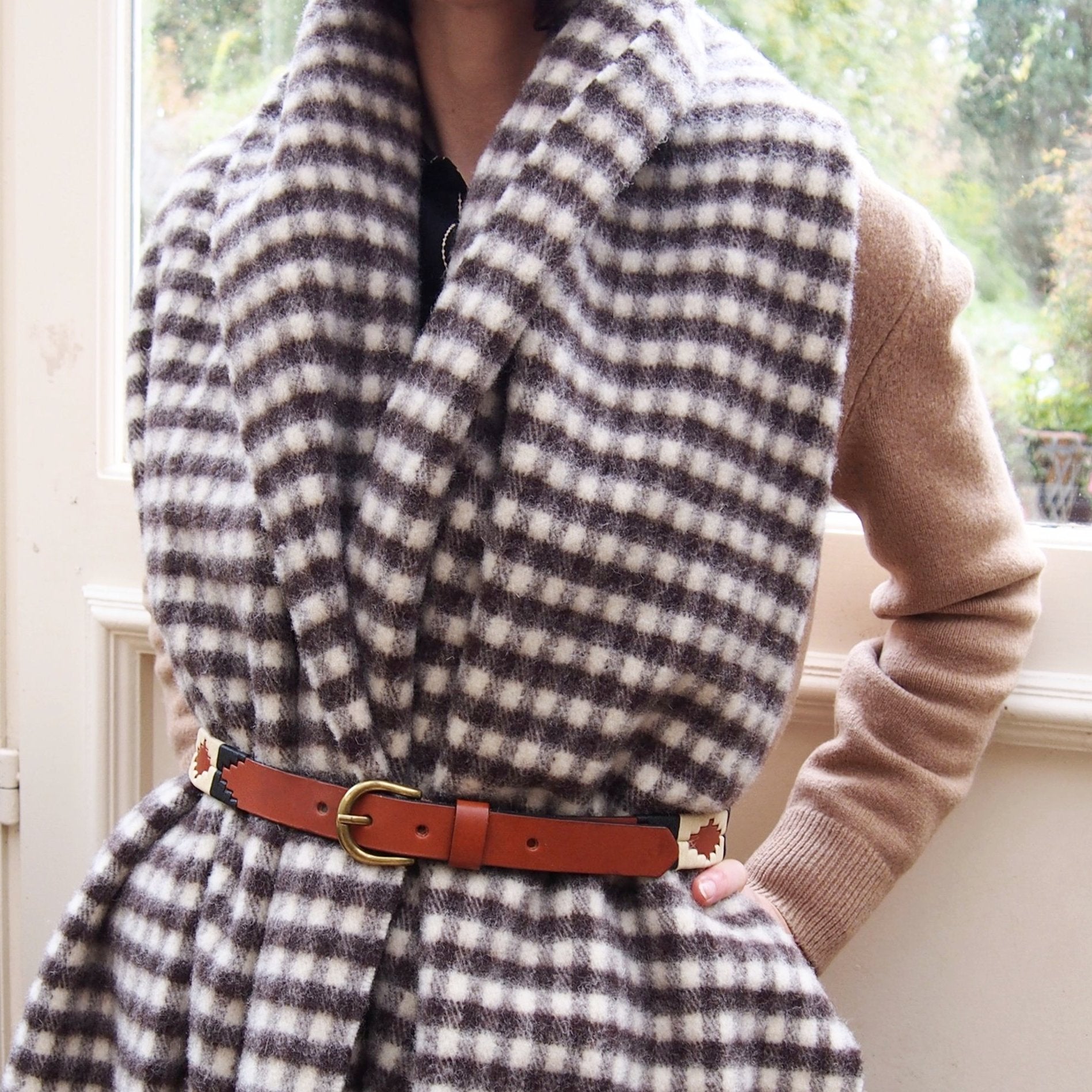 Femme portant un châle à carreaux vichy en laine espagnole et une ceinture de polo argentine. Woman wearing a Spanish wool vichy checked shawl and an argentinian polo belt.