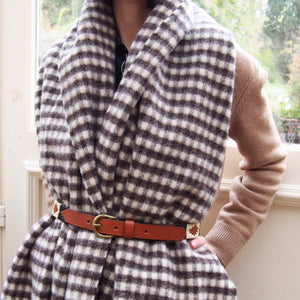Femme portant un châle à carreaux vichy en laine espagnole et une ceinture de polo argentine. Woman wearing a Spanish wool vichy checked shawl and an argentinian polo belt.
